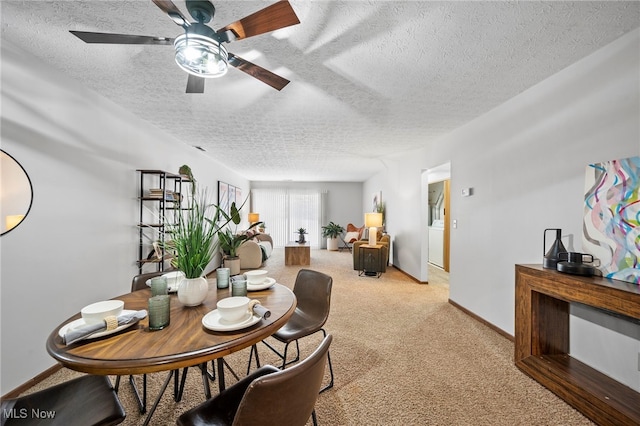 dining space featuring light carpet, a textured ceiling, and baseboards