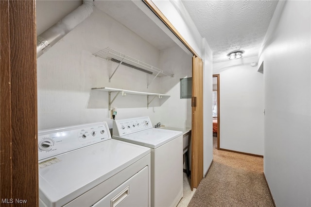 laundry area with a textured ceiling, light carpet, laundry area, baseboards, and washer and dryer