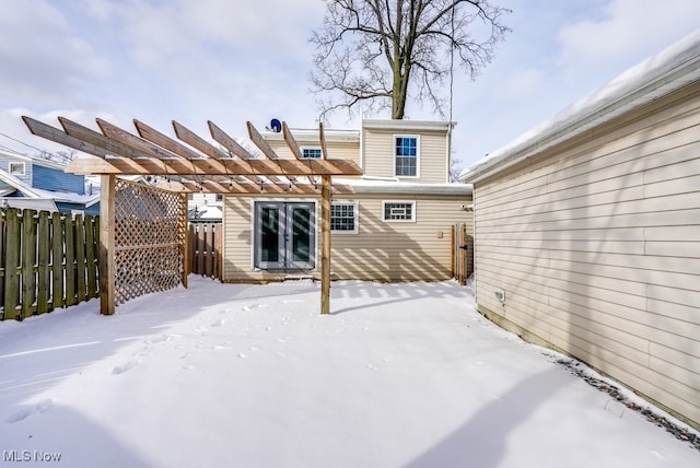 snow covered rear of property featuring fence and a pergola