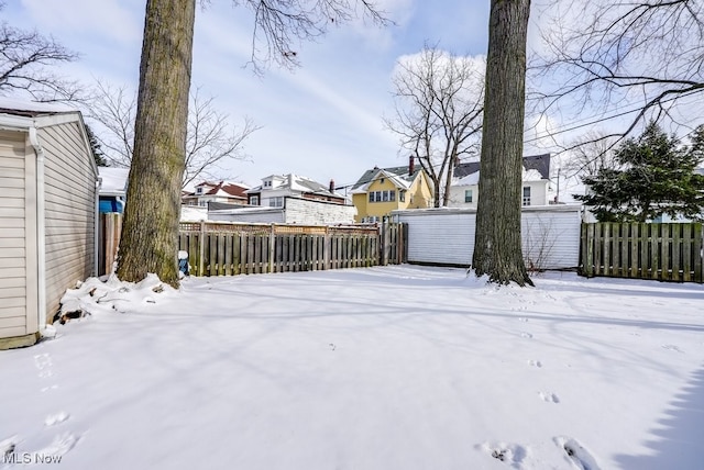 yard covered in snow with fence and a residential view