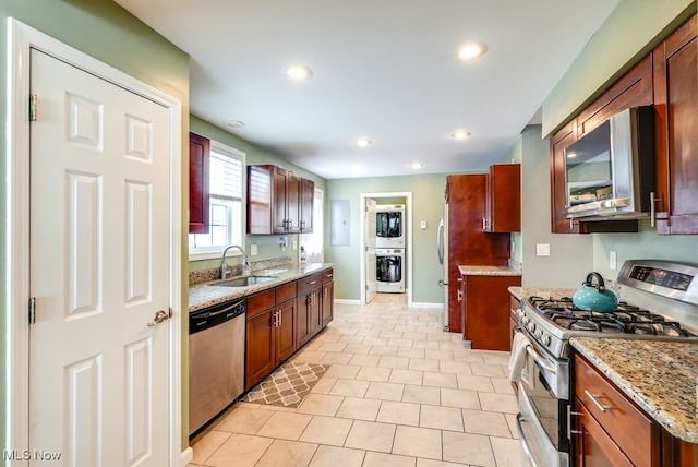 kitchen with recessed lighting, a sink, appliances with stainless steel finishes, light stone countertops, and washer / clothes dryer