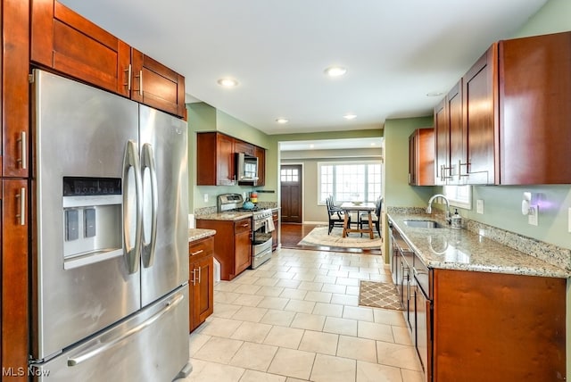 kitchen featuring light tile patterned floors, light stone counters, recessed lighting, a sink, and appliances with stainless steel finishes