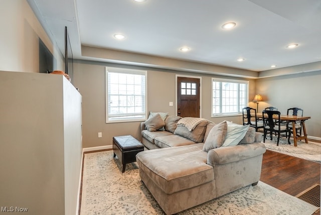 living room with light wood-type flooring, visible vents, baseboards, and recessed lighting