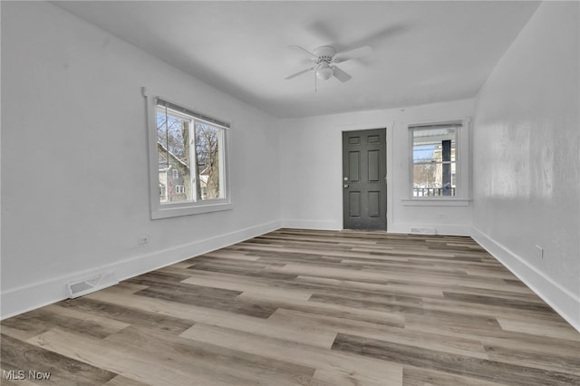 empty room featuring light wood finished floors, baseboards, visible vents, and a ceiling fan