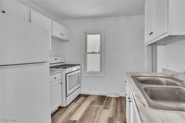 kitchen featuring white appliances, light countertops, a sink, and white cabinets