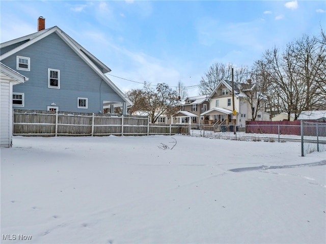 yard covered in snow featuring a residential view and fence