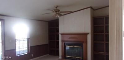 unfurnished living room with a glass covered fireplace and a ceiling fan