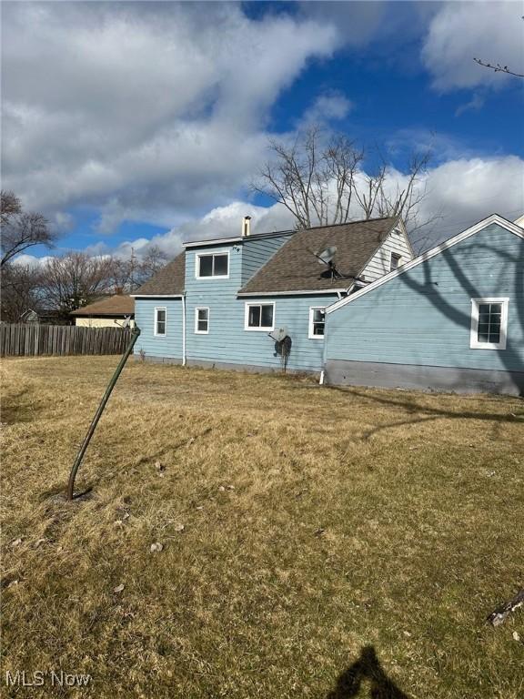 back of house with a lawn and fence