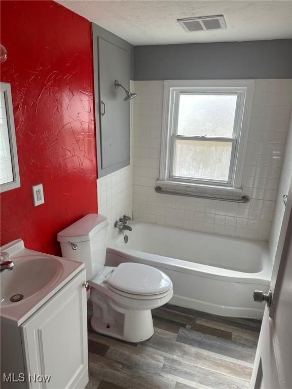 full bathroom with a textured ceiling, toilet, wood finished floors, vanity, and visible vents