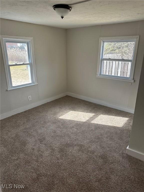 empty room with a textured ceiling, carpet, and baseboards