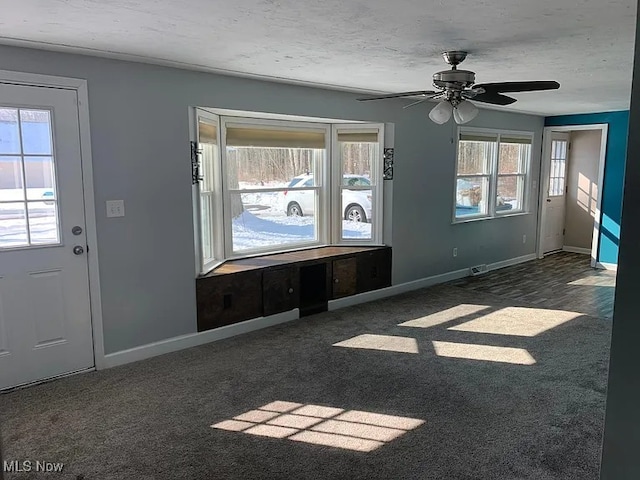 interior space with dark carpet, a textured ceiling, and baseboards