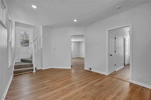 interior space featuring light wood-style floors, recessed lighting, stairway, and baseboards