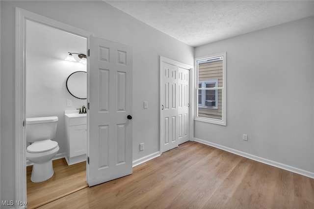 bathroom featuring toilet, vanity, a textured ceiling, wood finished floors, and baseboards