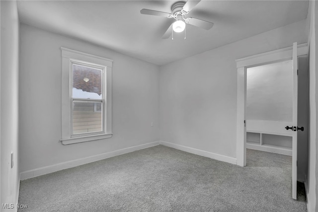 empty room with light carpet, a ceiling fan, and baseboards