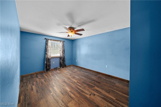 spare room featuring baseboards, a ceiling fan, and dark wood-style flooring