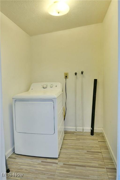 laundry room featuring a textured ceiling, laundry area, baseboards, light wood-type flooring, and washer / dryer