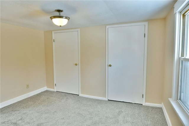 spare room featuring light carpet and baseboards