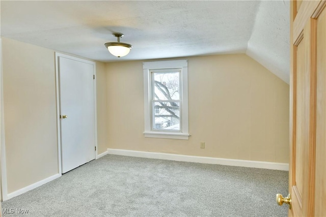 additional living space featuring light carpet, baseboards, a textured ceiling, and lofted ceiling