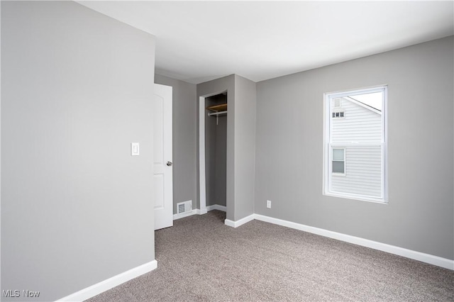 unfurnished bedroom with carpet floors, a closet, visible vents, and baseboards