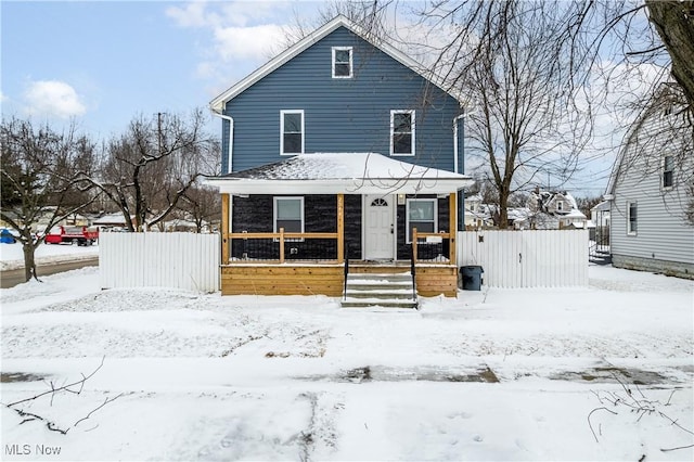 traditional style home with a porch and a fenced front yard