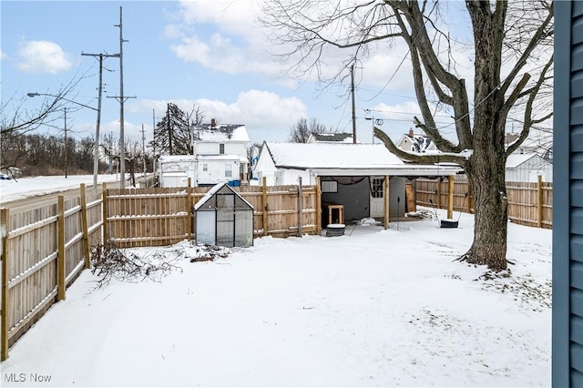 snowy yard with an outbuilding and a fenced backyard