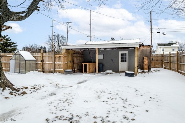 snow covered back of property with fence and an outdoor structure