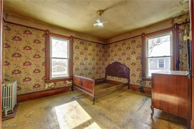 carpeted bedroom featuring wallpapered walls, radiator heating unit, and baseboards