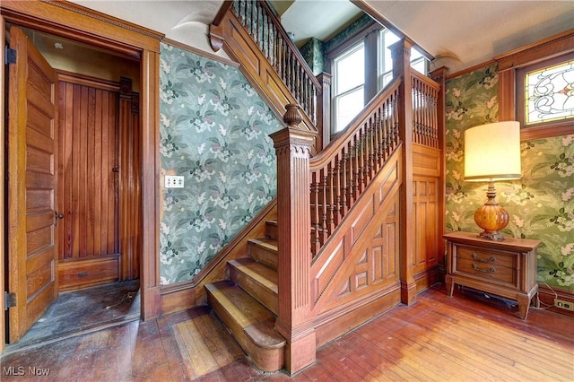 staircase featuring baseboards, wood finished floors, and wallpapered walls