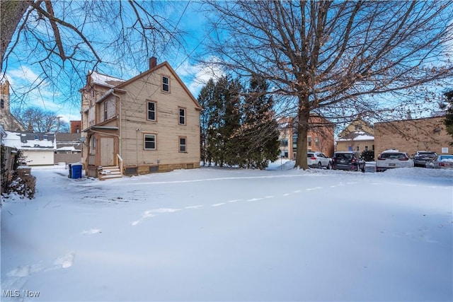 view of snow covered exterior with a chimney