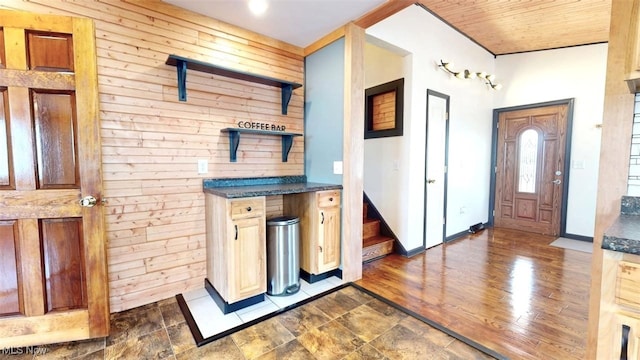 entryway featuring wooden walls, baseboards, wooden ceiling, stairway, and dark wood-type flooring