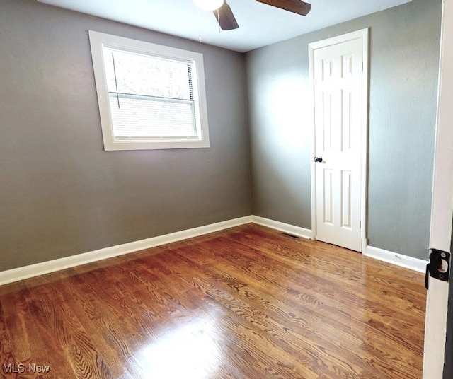 empty room with visible vents, baseboards, ceiling fan, and wood finished floors