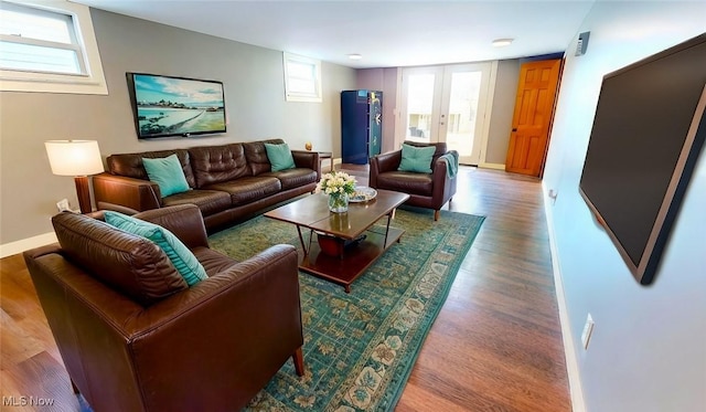 living area with baseboards, wood finished floors, and french doors