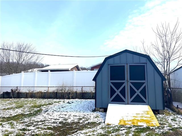 snow covered structure with a storage unit, an outdoor structure, and fence