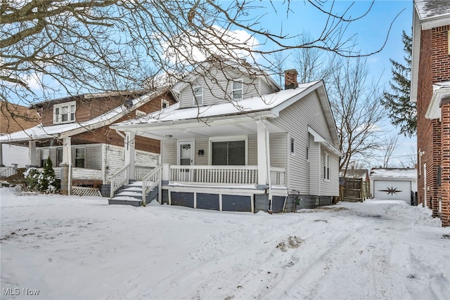 view of front of property featuring a garage, a chimney, and a porch