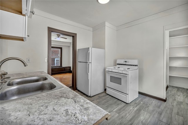 kitchen with white appliances, ornamental molding, light countertops, white cabinetry, and a sink