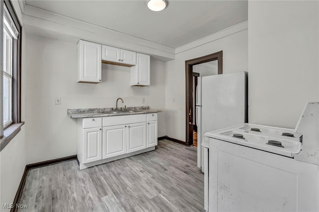 kitchen with light wood finished floors, light countertops, a healthy amount of sunlight, a sink, and white cabinetry