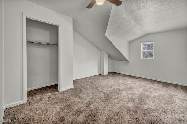 bonus room featuring baseboards, lofted ceiling, ceiling fan, carpet, and a textured ceiling