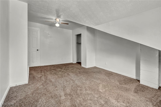 spare room featuring baseboards, a ceiling fan, lofted ceiling, dark colored carpet, and a textured ceiling