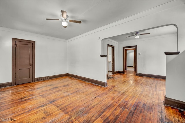 spare room featuring ceiling fan, baseboards, crown molding, and wood finished floors