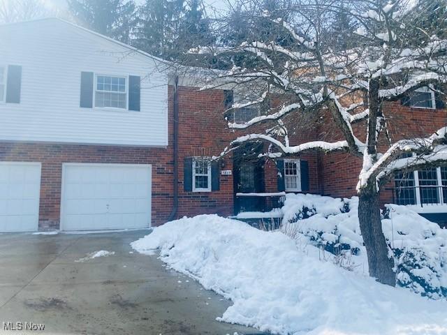 view of front facade with driveway, an attached garage, and brick siding