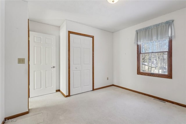 unfurnished bedroom with baseboards, a closet, visible vents, and light colored carpet