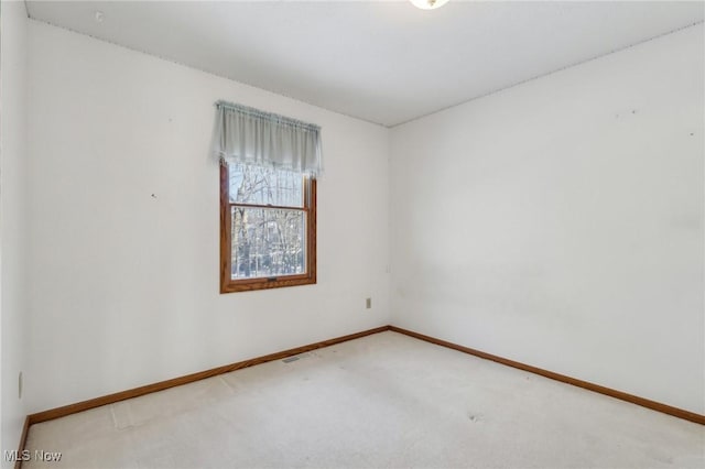 spare room with carpet flooring, visible vents, and baseboards