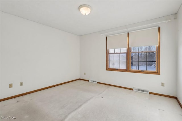 unfurnished room with carpet floors, visible vents, and baseboards