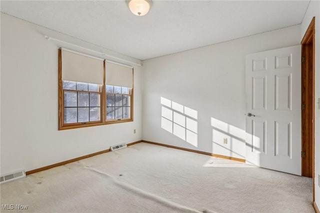 carpeted spare room featuring visible vents and baseboards