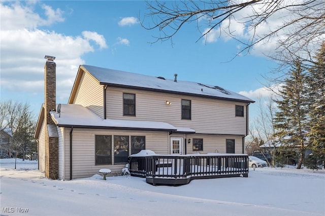 snow covered back of property featuring a chimney and a wooden deck