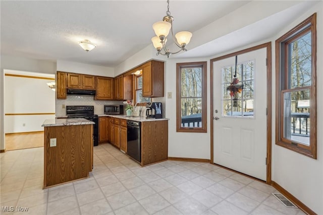 kitchen featuring pendant lighting, brown cabinets, visible vents, under cabinet range hood, and black appliances