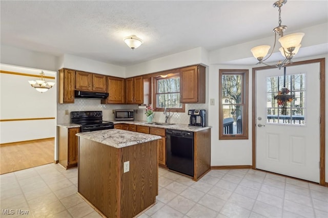 kitchen with black appliances, under cabinet range hood, an inviting chandelier, and decorative light fixtures