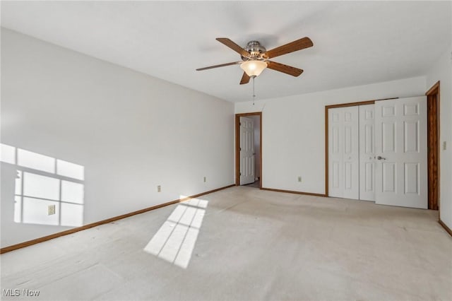 unfurnished bedroom with light carpet, ceiling fan, a closet, and baseboards