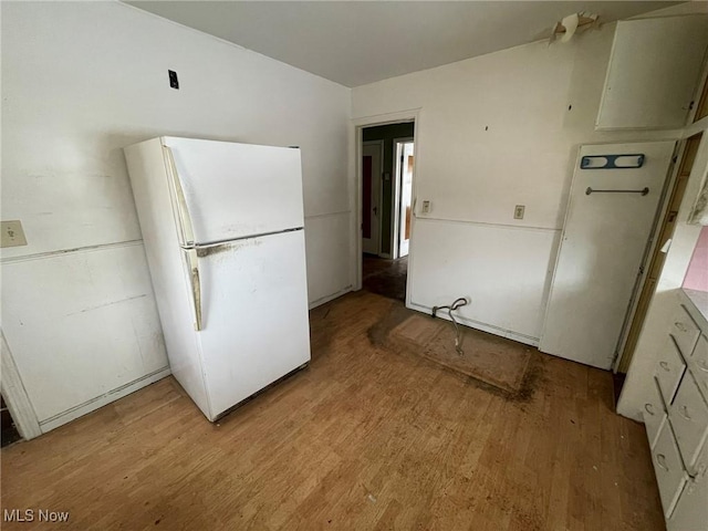 kitchen featuring light wood-type flooring, white cabinetry, light countertops, and freestanding refrigerator