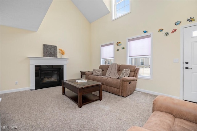 living area featuring baseboards, high vaulted ceiling, a fireplace with flush hearth, and light colored carpet